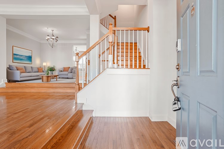 A wooden staircase with a white railing leads to the second floor of a house.