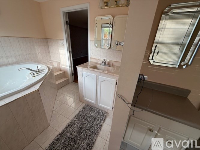 A bathroom with a tub, sink, and mirror.