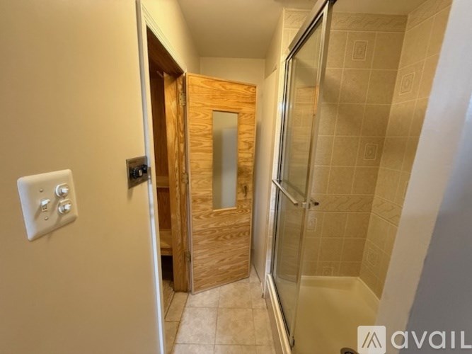 A bathroom with a glass shower door and a wooden door.