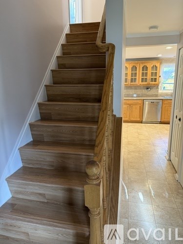 A wooden staircase with a carved balustrade leads to a kitchen.