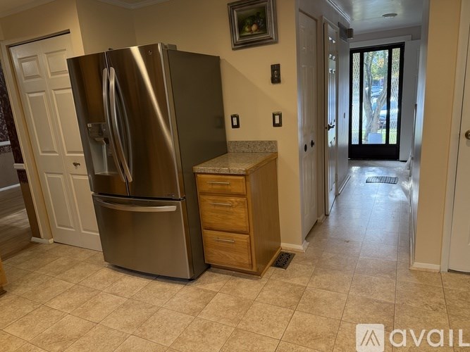 A kitchen with a stainless steel refrigerator and a countertop with a drawer underneath it.