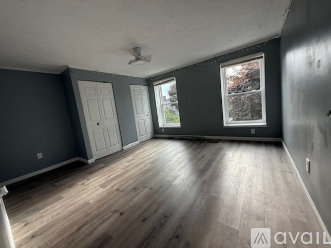 A room with grey walls and wooden flooring is available for rent.