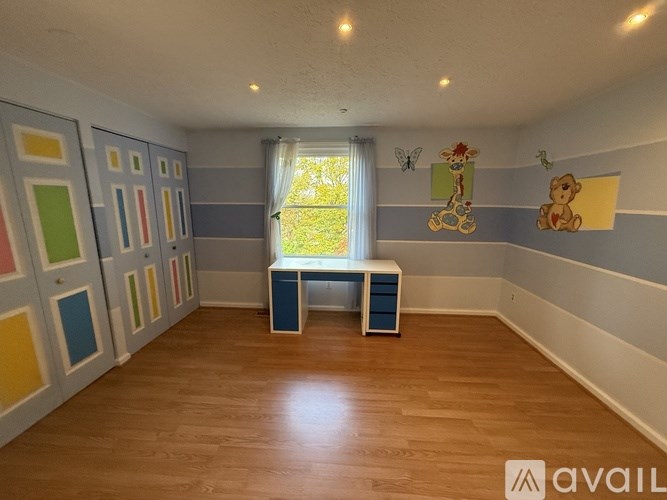 A room with a wooden floor and a window with a curtain.