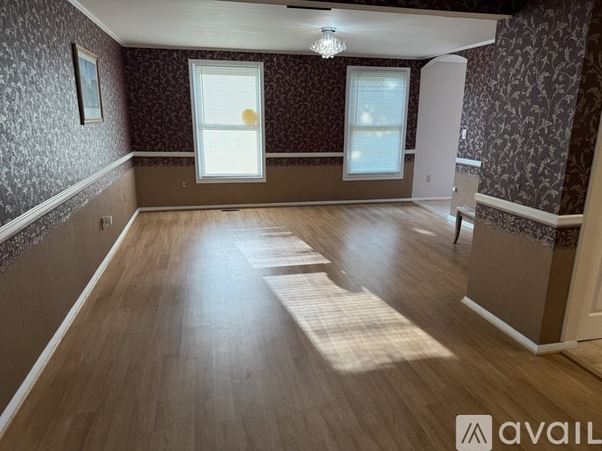 A room with wooden floors and patterned walls with a chandelier hanging from the ceiling.