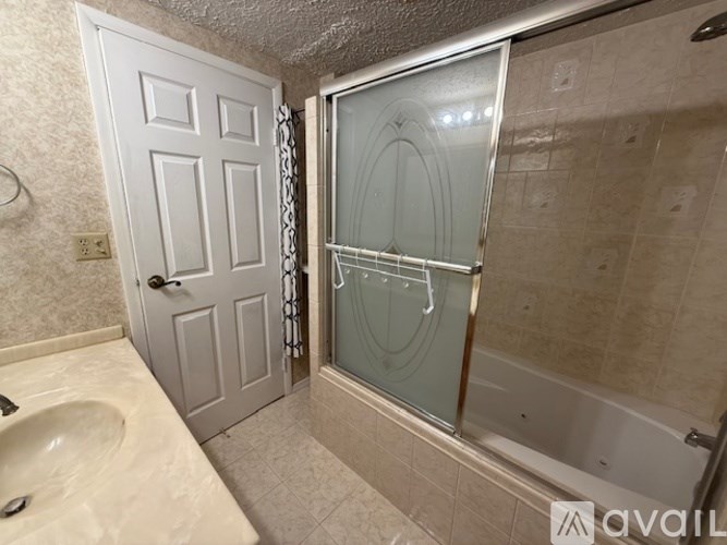 A bathroom with a glass shower door and a white door.