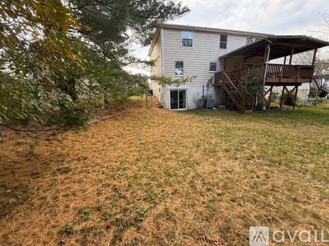 A house with a deck and a tree in front.