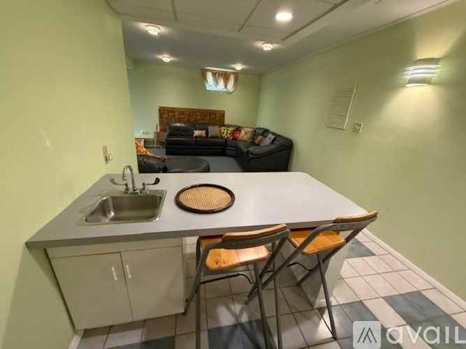 A kitchen with a sink, stove, and chairs.