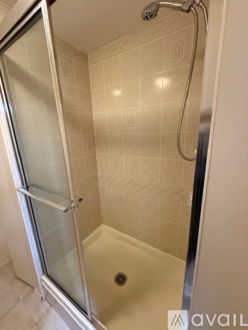 A shower area with a glass door and a tiled wall.