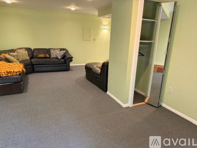 A living room with a black couch and a black ottoman.
