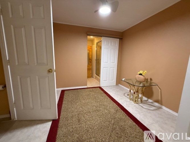 A hallway with a white door and a glass table with a gold base.