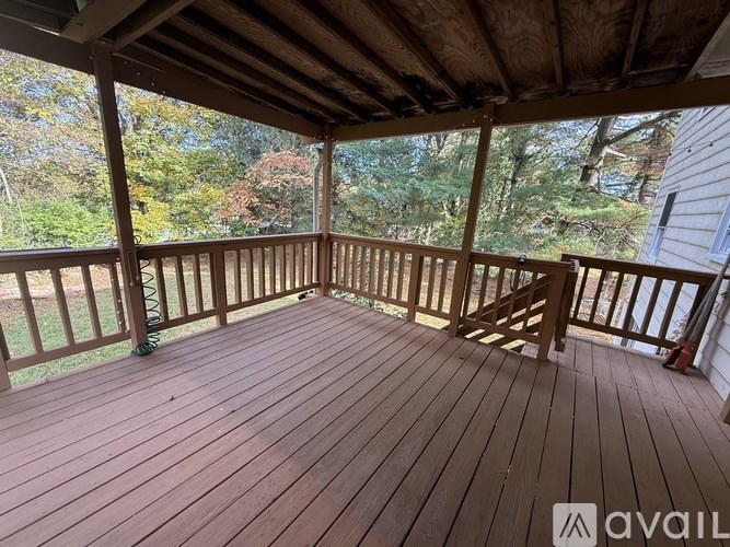 A wooden deck with a railing and a view of trees.