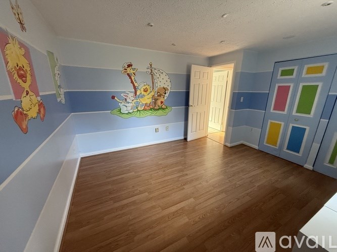 A room with wooden flooring and a mural of a cartoon character on the wall.