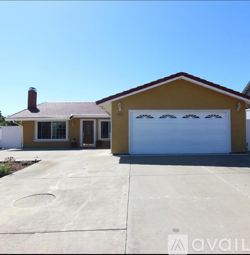 A yellow house with a white garage door and a red roof.