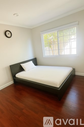 A bedroom with a bed, a clock, and a window.