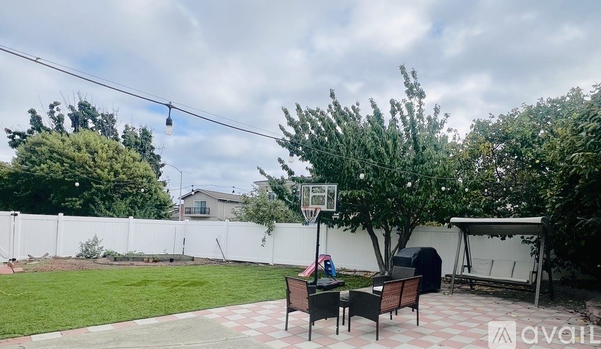 A backyard with a basketball hoop and a patio table set up.