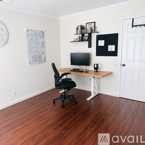 A room with a desk, chair, and a whiteboard on the wall.