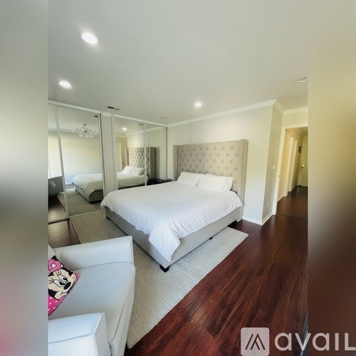 A bedroom with a large bed and a mirrored closet door.
