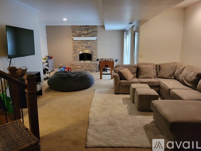 A living room with a stone fireplace and a large couch.