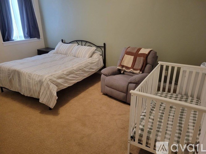 A baby's room with a crib, a bed, and a chair.