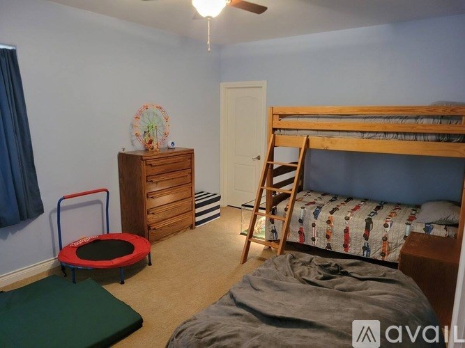 A room with a bed, a dresser, a chair, and a trampoline.