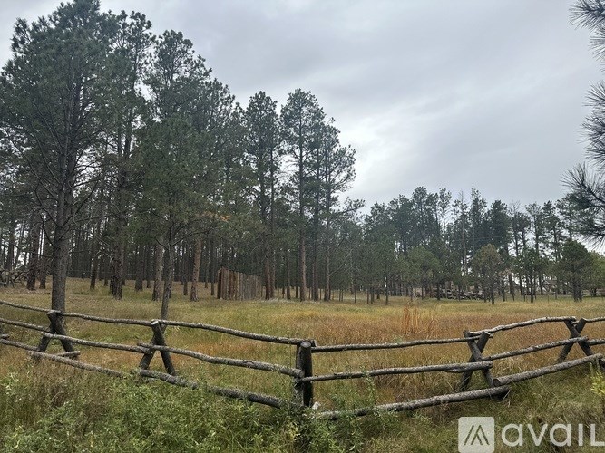 A fence in a field with trees in the background.