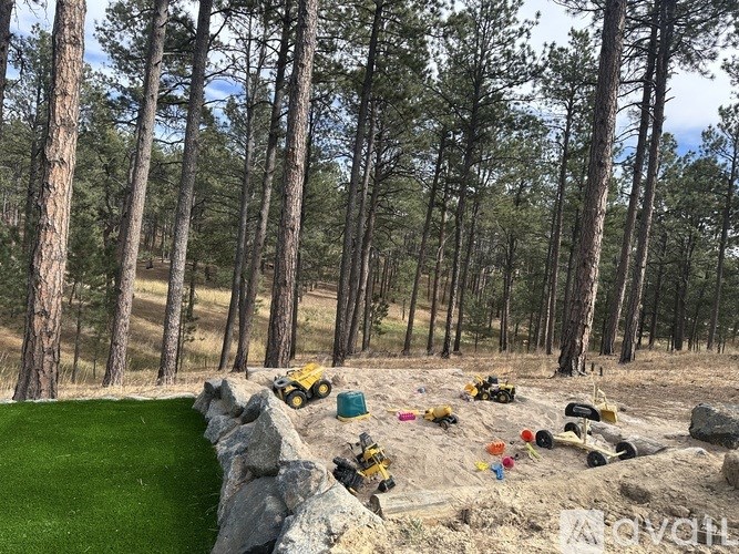A group of toy construction vehicles are scattered on a dirt path in a forest.