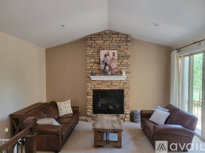 A living room with a stone fireplace and two brown couches.
