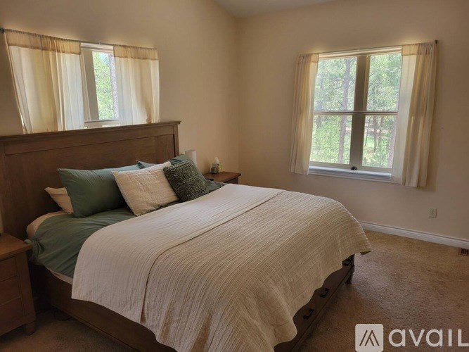 A bedroom with a large bed and a window with curtains.
