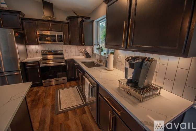 A modern kitchen with dark wood cabinets and stainless steel appliances.