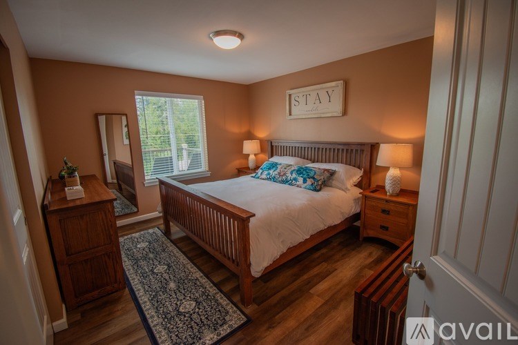 A bedroom with a bed, nightstand, and a rug.