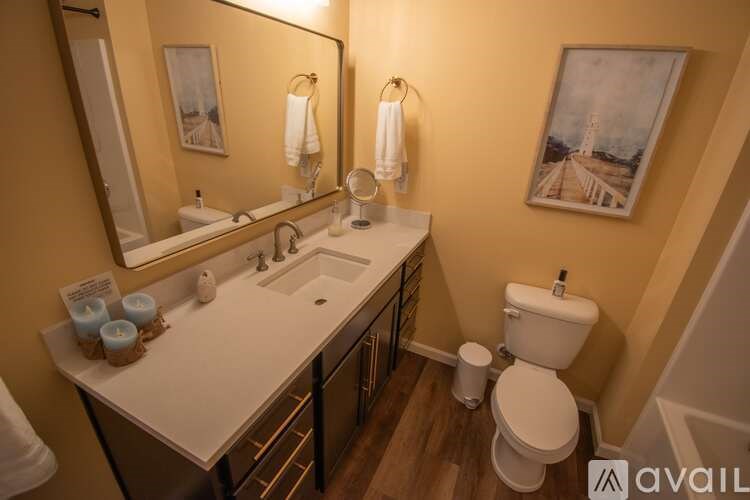A bathroom with a toilet, sink, and mirror.