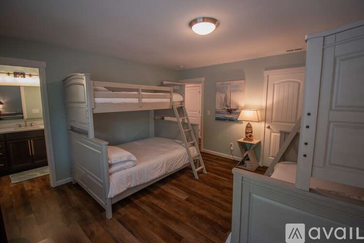 A white bunk bed in a room with wooden floors and a ladder.