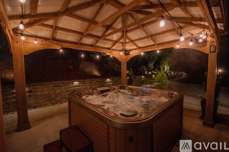 A hot tub is surrounded by a wooden structure with lights hanging from the ceiling.