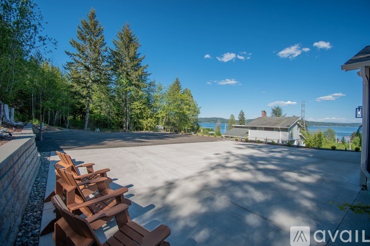 A sunny day at a park with wooden chairs and a house in the background.