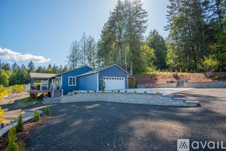 A blue house with a gravel driveway in front of it.