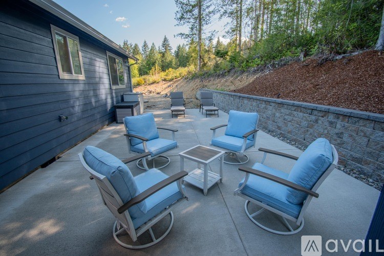 A set of six blue chairs are arranged around a square table on a patio.