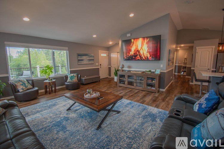 A modern living room with a large screen TV and a fireplace.