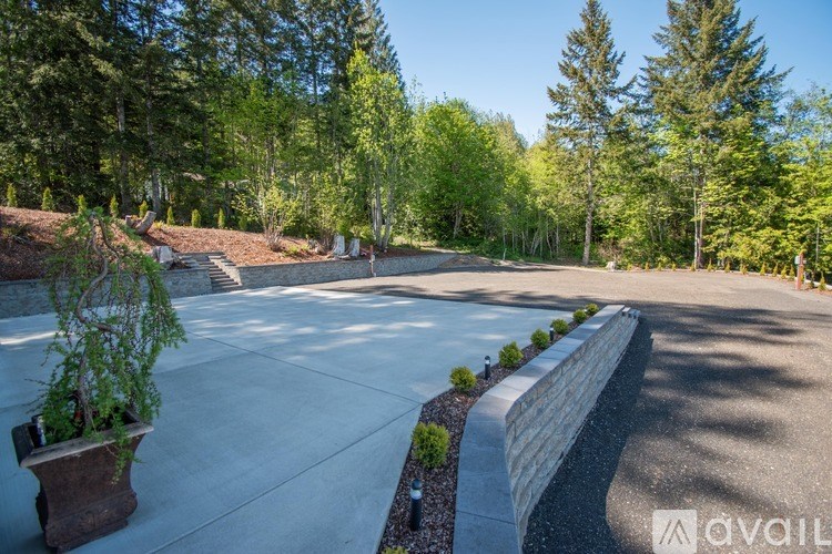 A driveway with a stone wall and a potted plant.