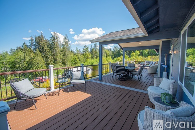 A wooden deck with chairs and a table is surrounded by trees.