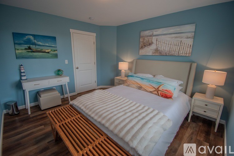 A bedroom with a bed, nightstands, and a desk with a painting on the wall.