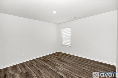 A room with wooden flooring and a window with blinds.
