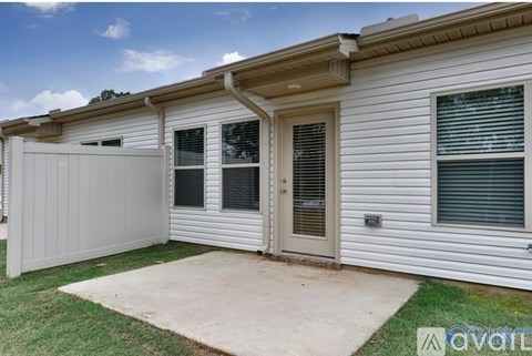 A small white house with a brown roof and a grey garage door.