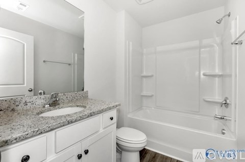 A white bathroom with a marble countertop and a white toilet.