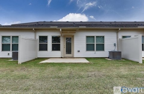 A white house with a grey roof and a green lawn in front.