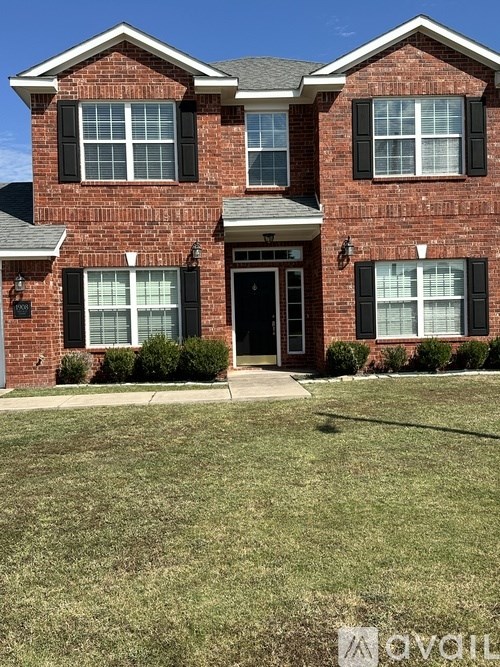 A red brick house with a black front door and two windows on either side.