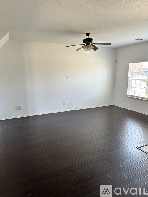 A room with a ceiling fan and wooden flooring.