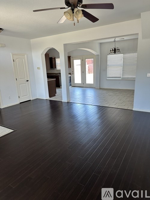 A spacious room with a ceiling fan and hardwood flooring.