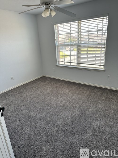 A room with a ceiling fan and a window with blinds.