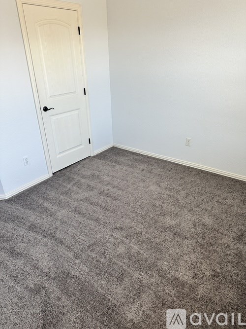A room with a carpeted floor and a white door.
