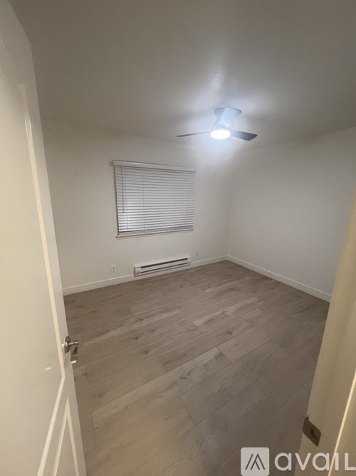 A room with wooden flooring and a window with blinds.